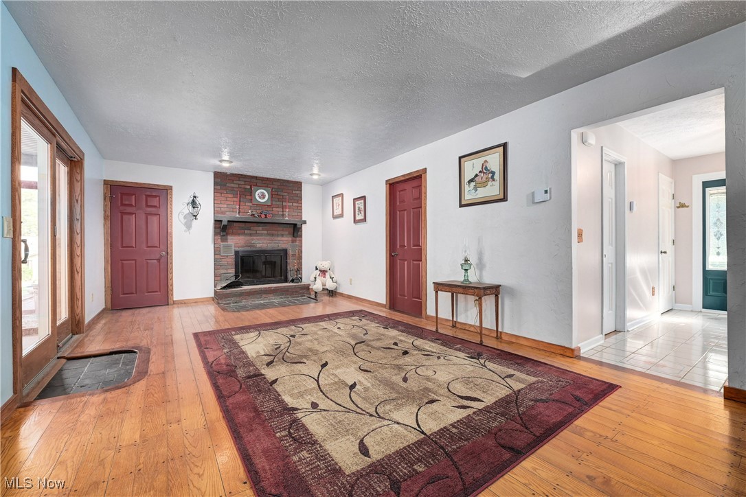 1820 Claus Road Vermilion, OH 44089 - Photo 3 of 10 Living room featuring a textured ceiling, light hardwood / wood-style flooring, and a brick fireplace
