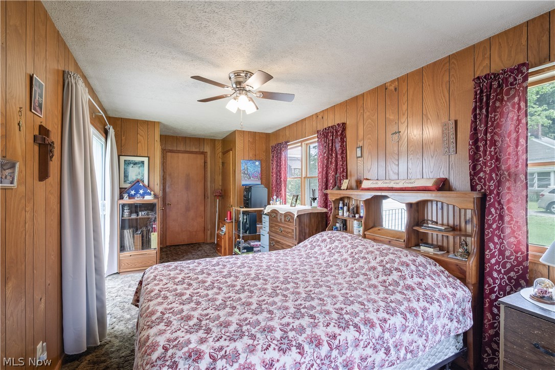 6324 Struthers Road Youngstown, OH 44514 - Photo 33 of 42 Room featuring wood-finish paneling, a textured ceiling, a ceiling fan with integrated lighting, and multiple windows
