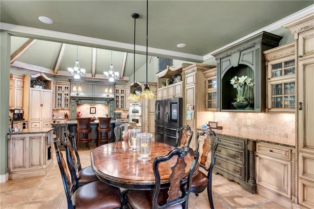 a kitchen with stainless steel appliances kitchen island granite countertop a table chairs and a chandelier