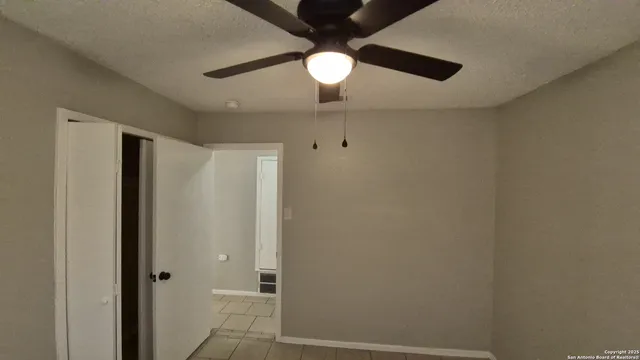 an empty room with a chandelier fan and windows