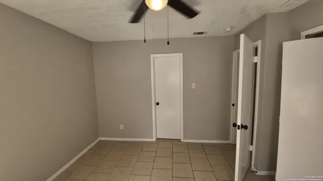 a view of small backyard with large trees and wooden fence
