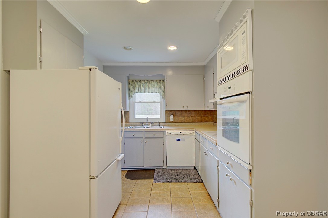 1373 Fitchetts Wharf Road Moon, VA 23119 - Photo 9 of 22 Kitchen with white appliances, backsplash, light tile floors, and white cabinets