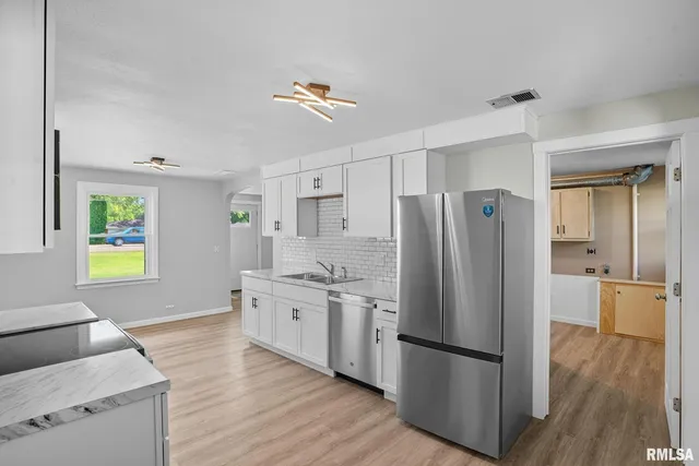 a kitchen with stainless steel appliances a refrigerator sink and wooden floor