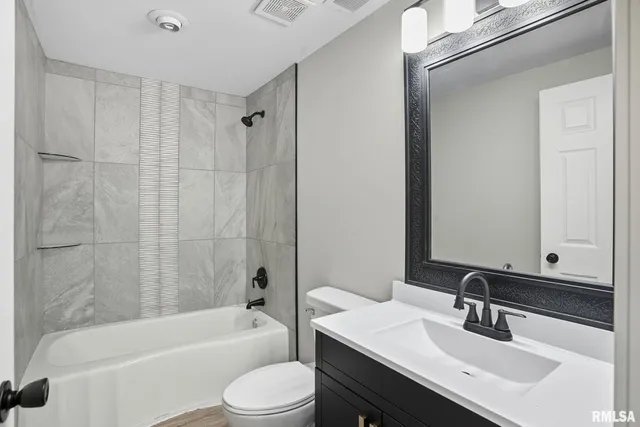 a bathroom with a bathtub shower sink vanity mirror and toilet