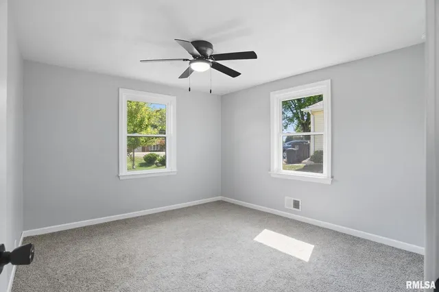 an empty room with windows and fan
