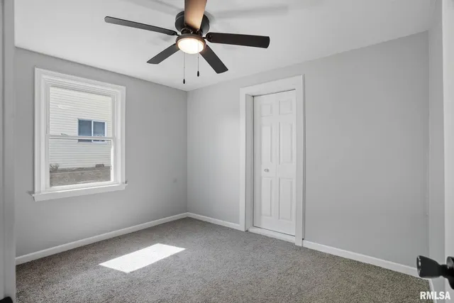 an empty room with a window and a fan