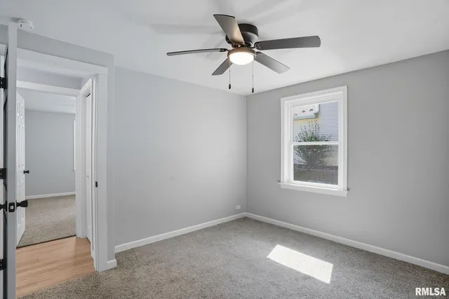 an empty room with window and a ceiling fan