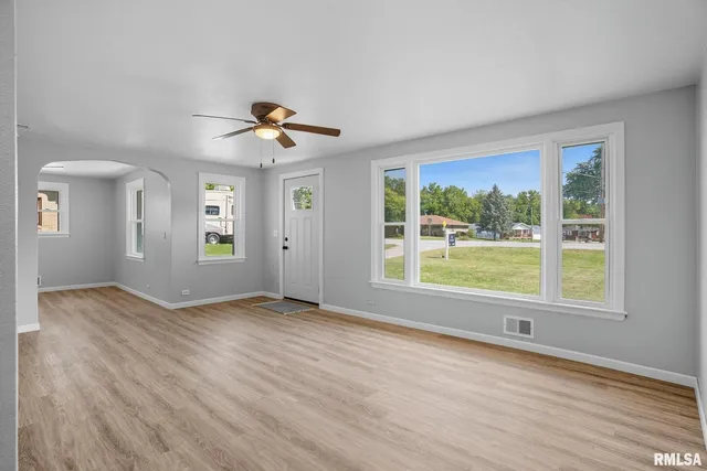 a view of an empty room with a window and wooden floor