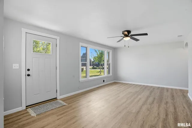a view of an empty room with a window and wooden floor