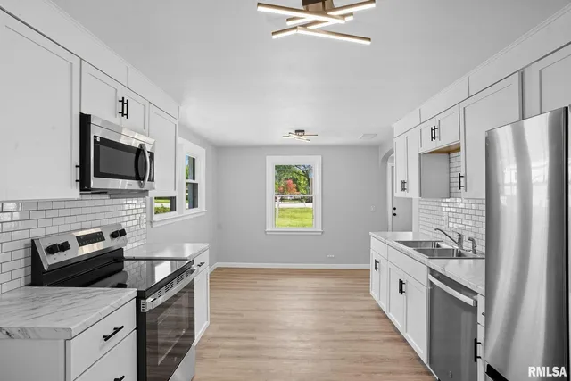a kitchen with a sink appliances and wooden floor