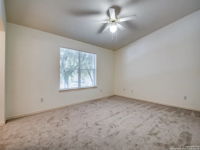 an empty room with a chandelier fan and windows