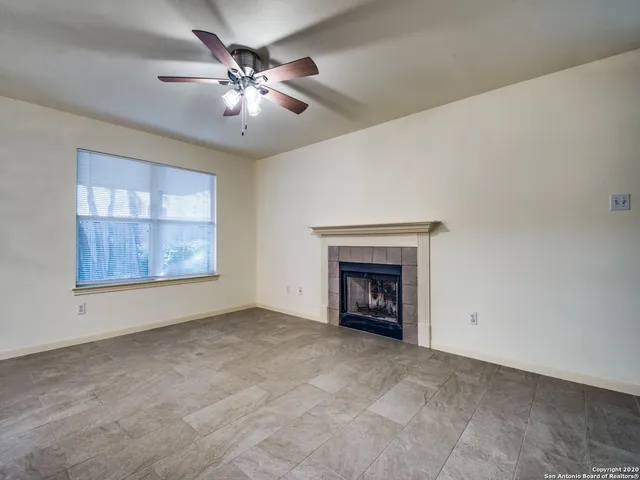 a view of an empty room with chandelier fan and fire place