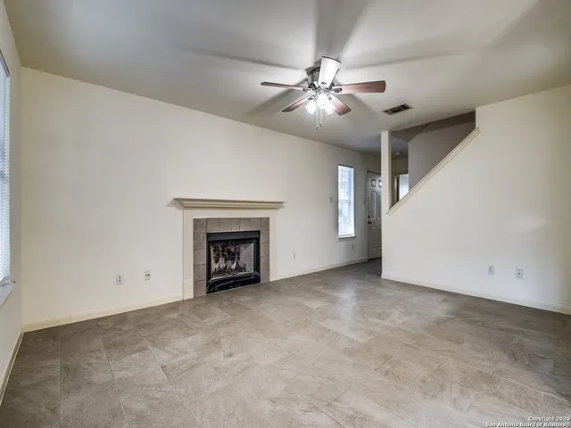 a view of an empty room with chandelier fan and fire place