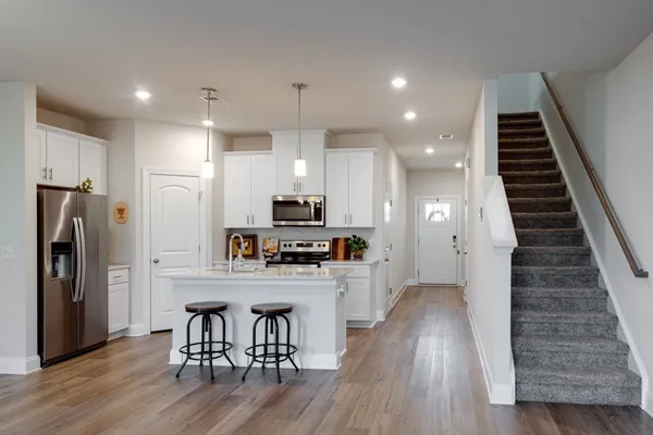 a kitchen with refrigerator a stove and wooden floor
