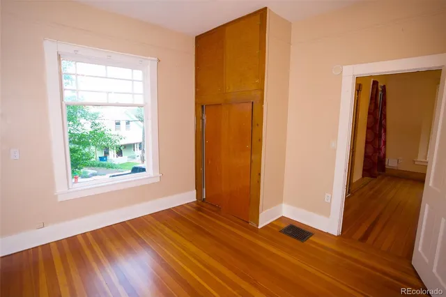 a view of an empty room with wooden floor and a window