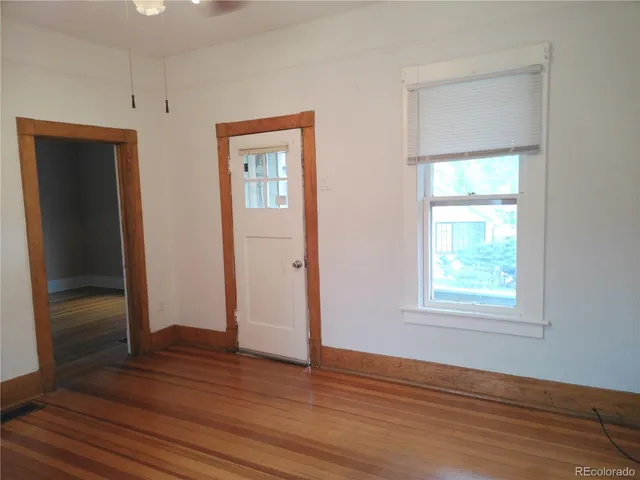 an empty room with wooden floor closet and windows