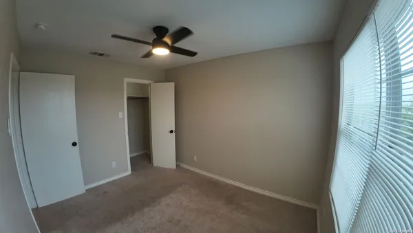 an empty room with ceiling fan and window