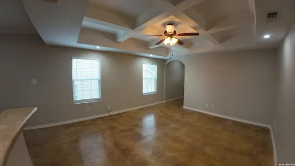 an empty room with chandelier fan and windows