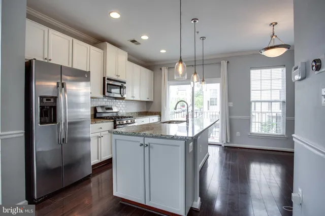 a kitchen with stainless steel appliances granite countertop a refrigerator a sink dishwasher a stove and a refrigerator with wooden floor