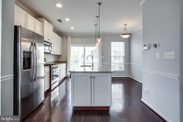 a kitchen with stainless steel appliances granite countertop a refrigerator a sink dishwasher a stove and white cabinets with wooden floor