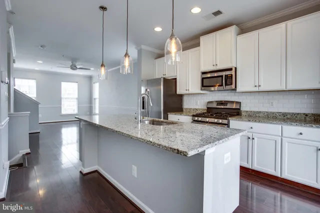 a kitchen with stainless steel appliances granite countertop a sink a stove and a wooden floors