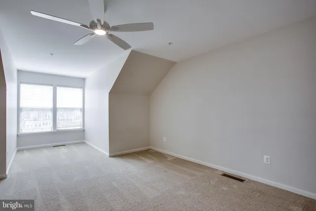 an empty room with a ceiling fan and windows