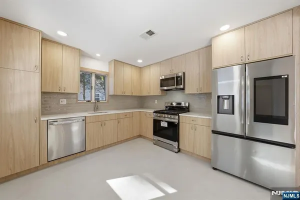a large kitchen with cabinets a sink and stainless steel appliances