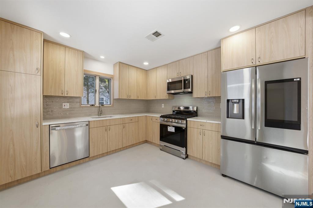 40 Magnolia Avenue Tenafly, NJ 07670 - Photo 13 of 48 a kitchen with a refrigerator a sink and white cabinets