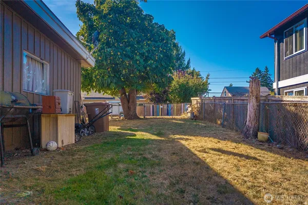 a view of a backyard with wooden fence and a large tree