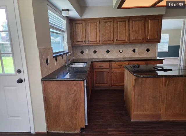 a kitchen with granite countertop a sink stove and cabinets