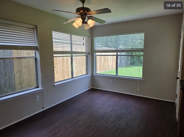 a view of an empty room with wooden floor and a window