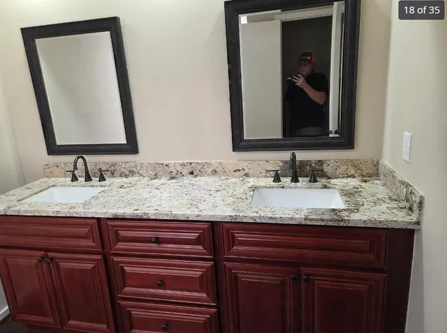 a bathroom with a granite countertop sink and a mirror