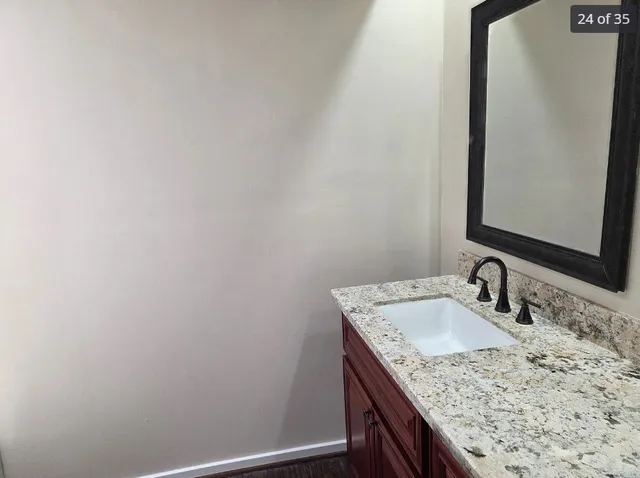 a bathroom with a granite countertop sink and a mirror