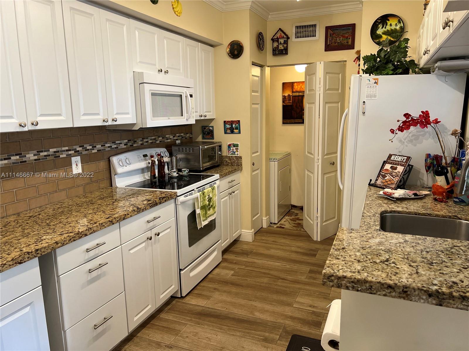 17100 North Bay Road, Unit 1701 Sunny Isles Beach, FL 33160 - Photo 18 of 84 a kitchen with stainless steel appliances granite countertop a stove a sink and white cabinets with wooden floor