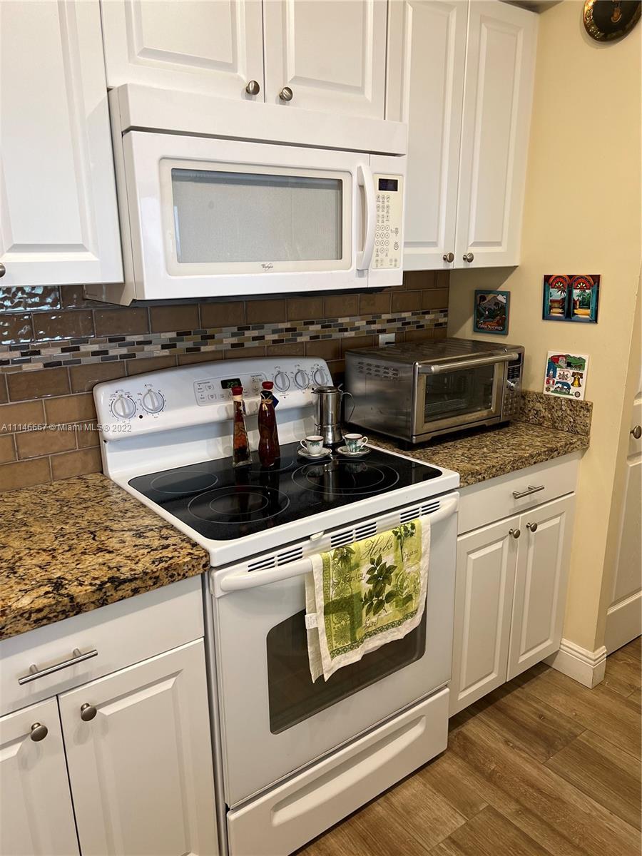 17100 North Bay Road, Unit 1701 Sunny Isles Beach, FL 33160 - Photo 22 of 84 a kitchen with granite countertop white cabinets and stainless steel appliances