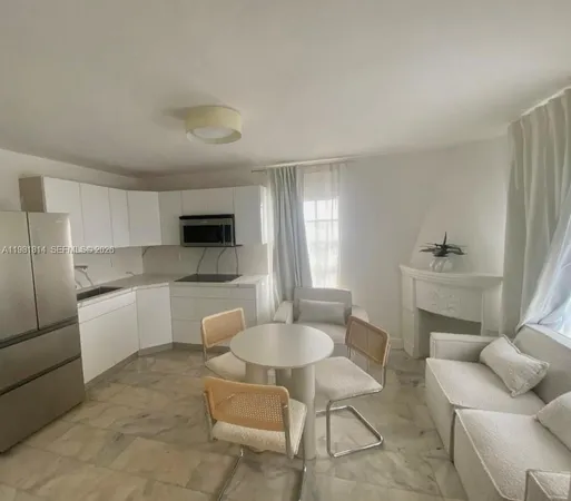 a kitchen with a dining table chairs sink and white cabinets