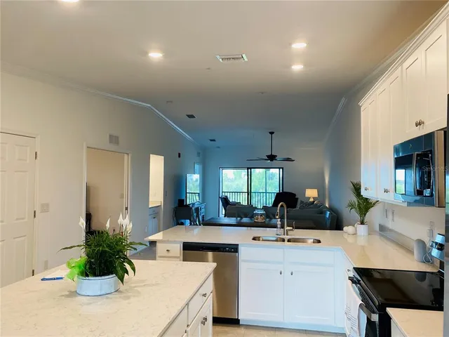 a kitchen with stainless steel appliances a sink a counter top space cabinets and a potted plant