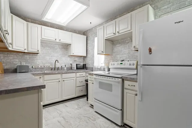 a kitchen with granite countertop white cabinets and white appliances