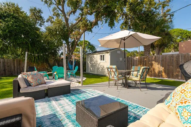 a view of a patio with couches table and chairs under an umbrella