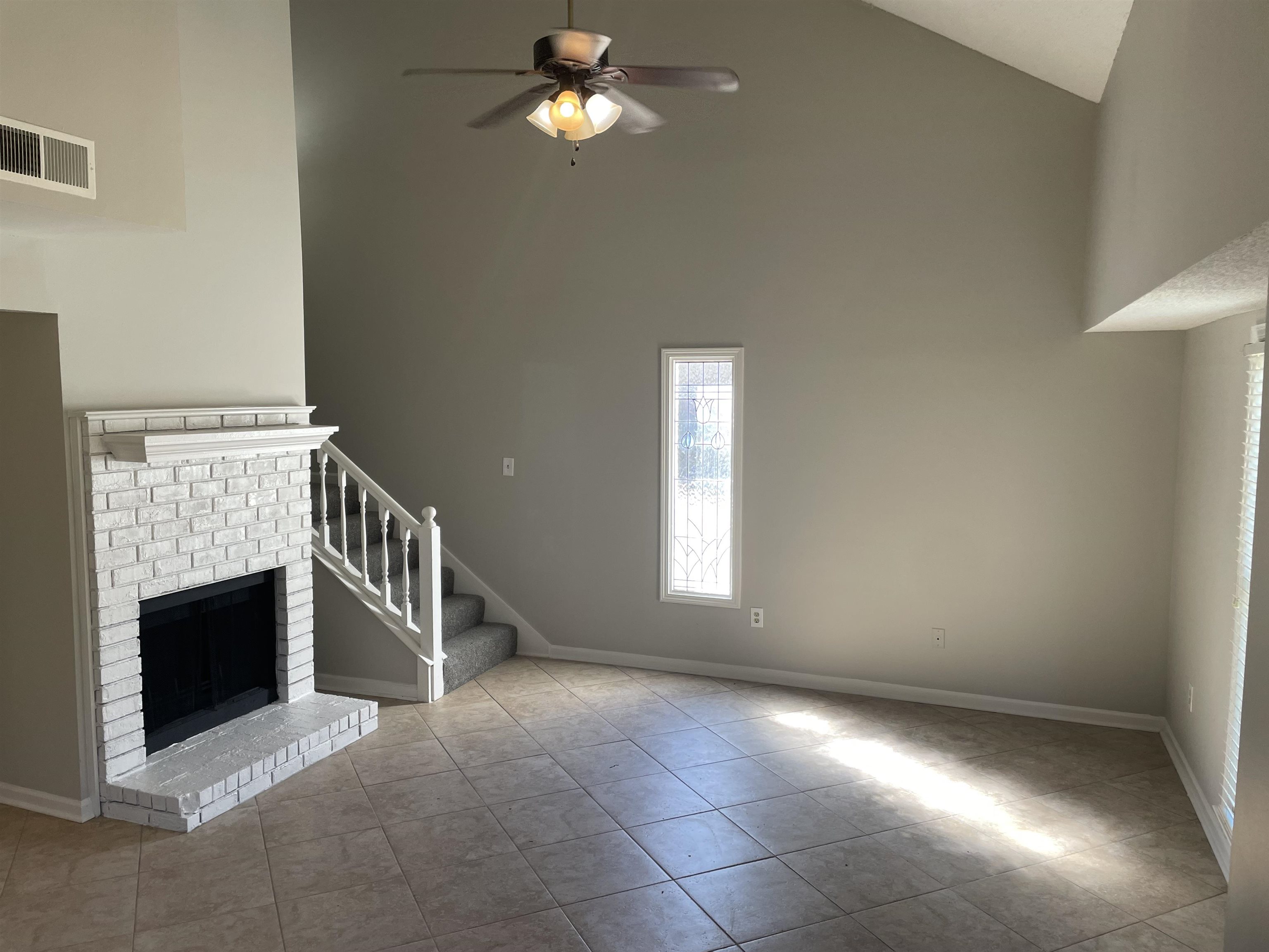 242 South Walnut Bend Road Memphis, TN 38018 - Photo 4 of 17 Unfurnished living room with ceiling fan, high vaulted ceiling, light tile patterned floors, and a brick fireplace