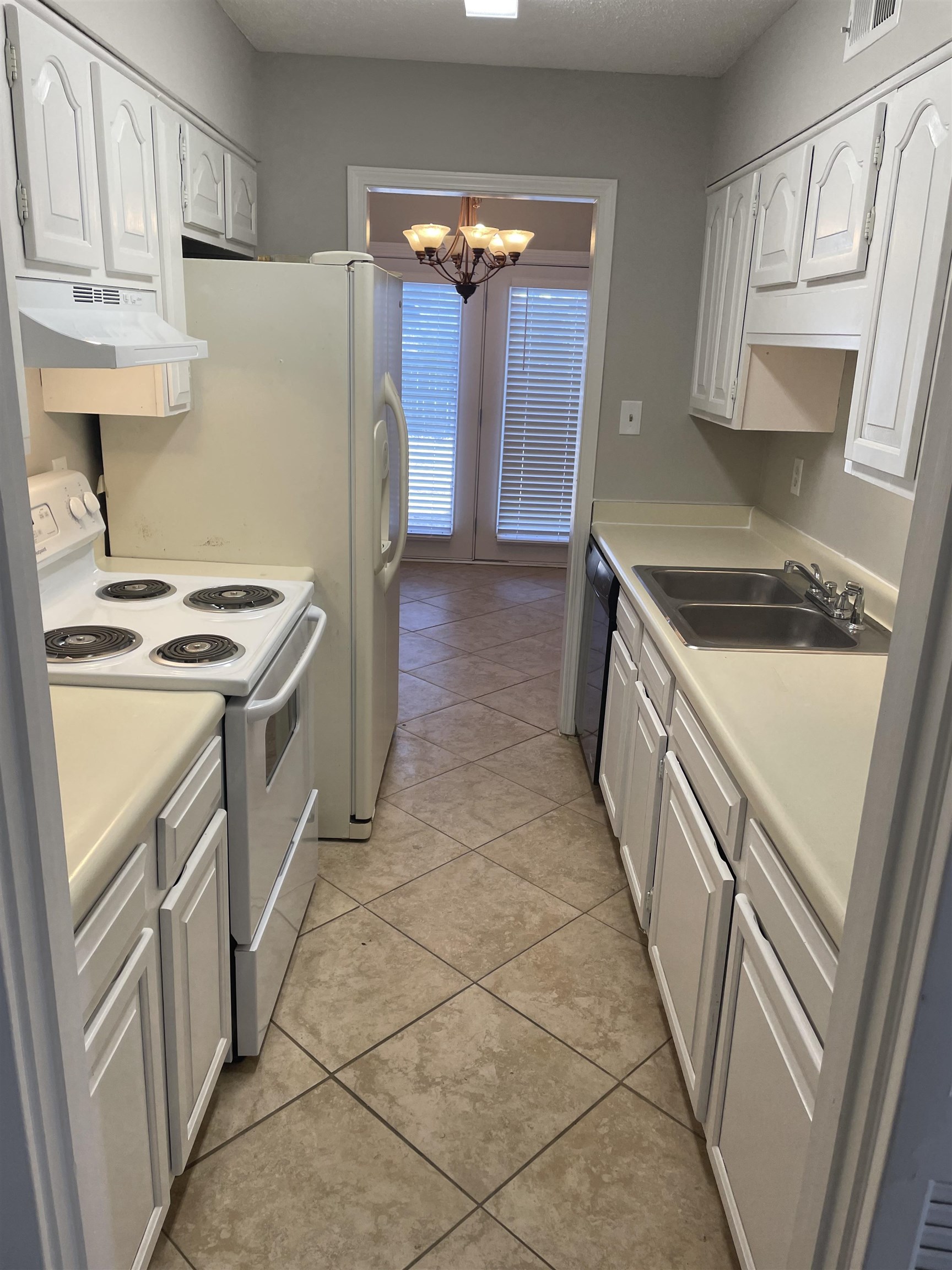 242 South Walnut Bend Road Memphis, TN 38018 - Photo 6 of 17 Kitchen featuring white cabinetry, white range with electric cooktop, a notable chandelier, and light tile patterned flooring