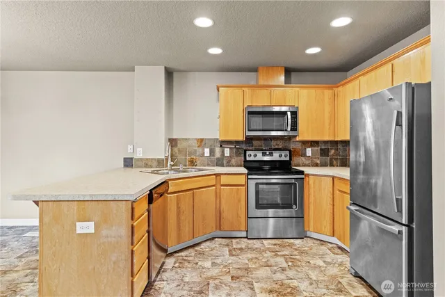 a kitchen with stainless steel appliances granite countertop a refrigerator a stove top oven a sink and dishwasher