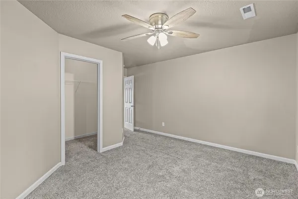 an empty room with a chandelier fan and windows