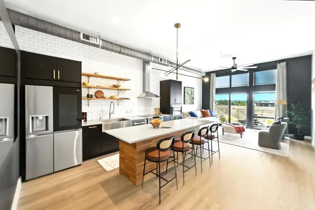 a view of a dining room and livingroom with furniture wooden floor a rug a flat screen tv a rug and a chandelier