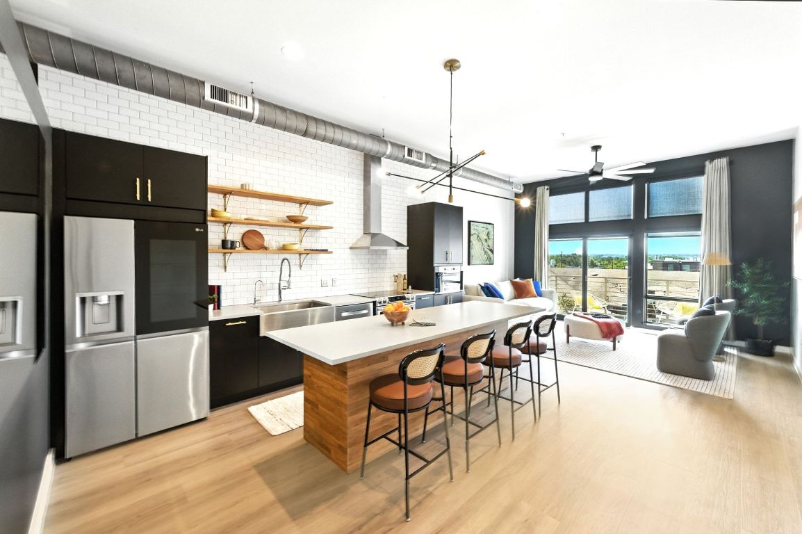 a view of a dining room and livingroom with furniture wooden floor a rug a flat screen tv a rug and a chandelier