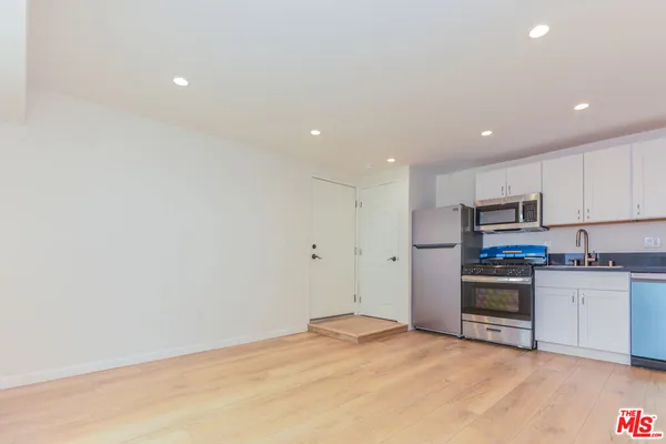 a view of a kitchen with a sink and dishwasher a refrigerator with wooden floor