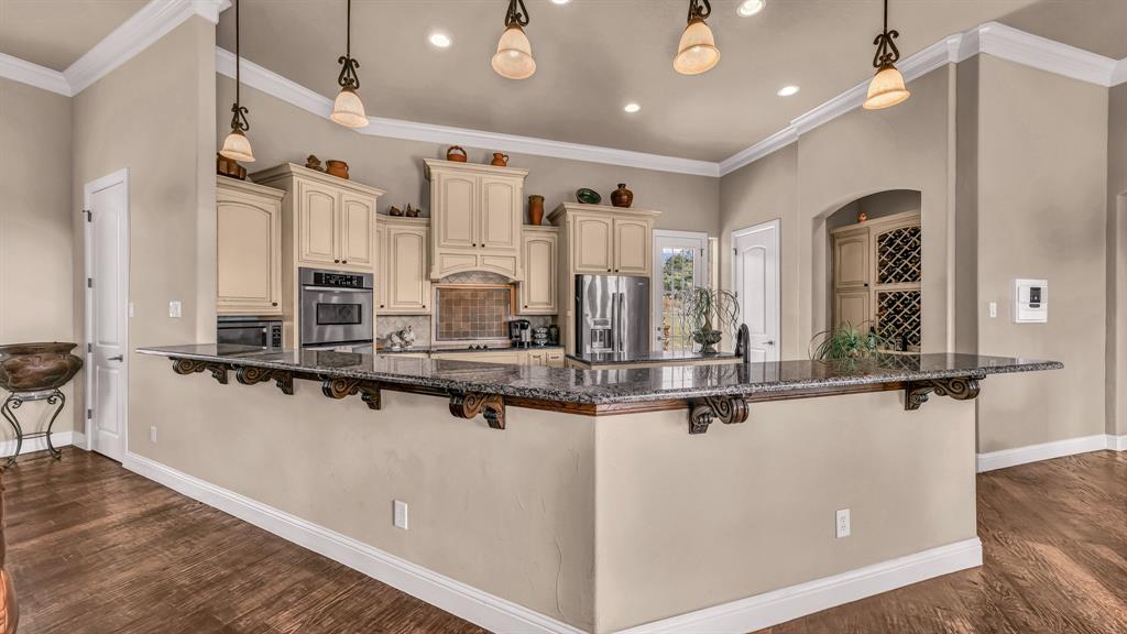 840 Hensley Road Gordon, TX 76453 - Photo 11 of 40 Kitchen with baseboards, a breakfast bar area, cream cabinets, backsplash, and stainless steel appliances