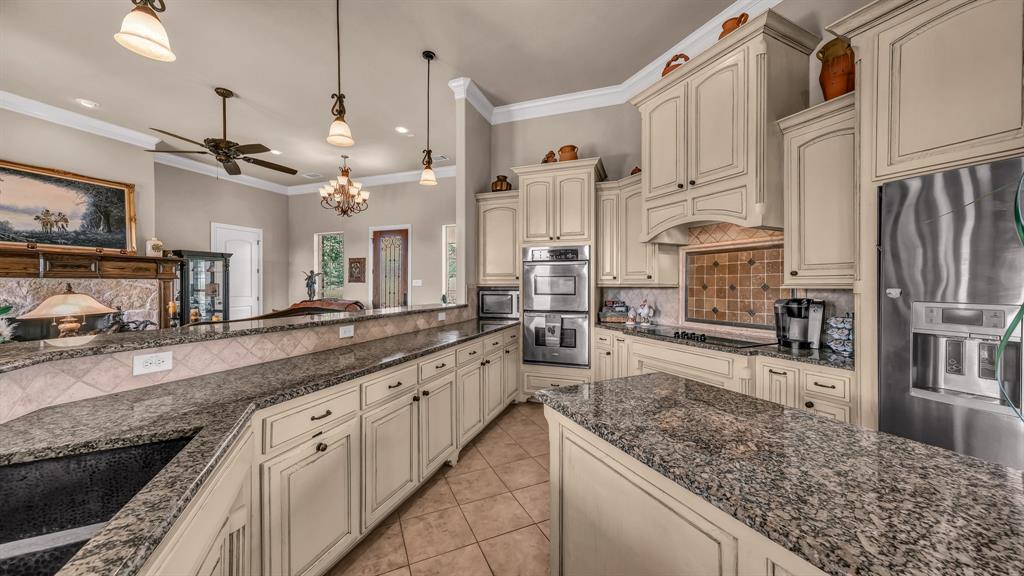 840 Hensley Road Gordon, TX 76453 - Photo 14 of 40 Kitchen with cream cabinets, crown molding, appliances with stainless steel finishes, ceiling fan with notable chandelier, and light tile patterned floors