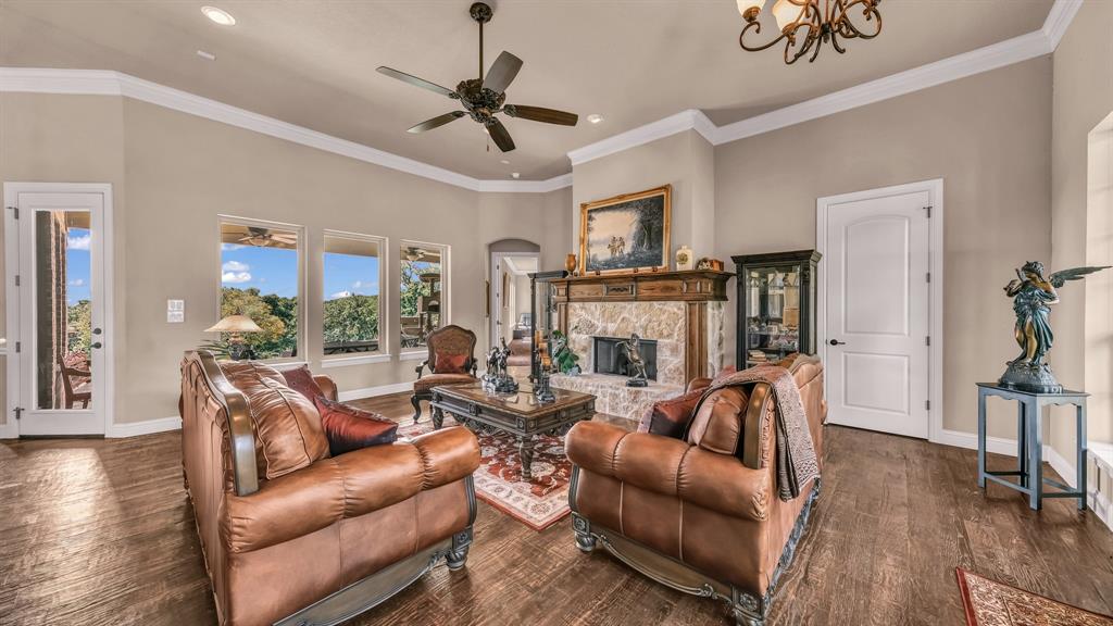 840 Hensley Road Gordon, TX 76453 - Photo 5 of 40 Living room featuring dark wood-style flooring, a stone fireplace, ceiling fan with notable chandelier, recessed lighting, and baseboards