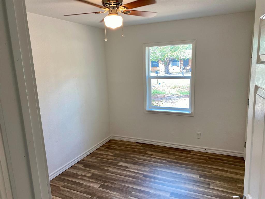 100 Burl Street Corinth, TX 76208 - Photo 6 of 16 an empty room with wooden floor fan and windows